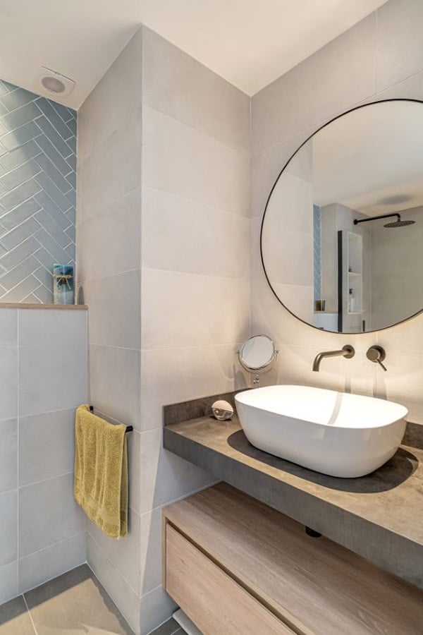 Baño con espejo redondo y pica moderna