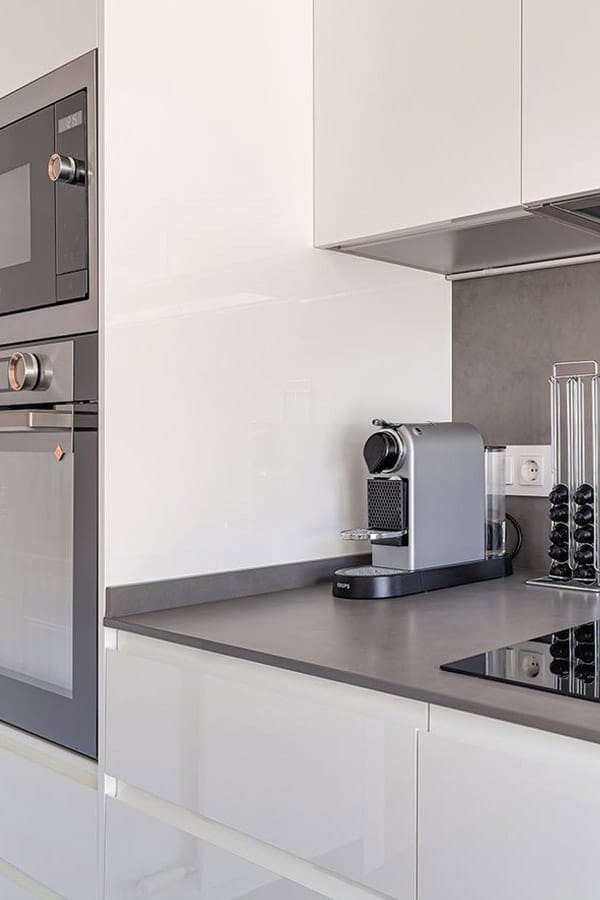 Lateral de una cocina en blanco con electrodomésticos en gris