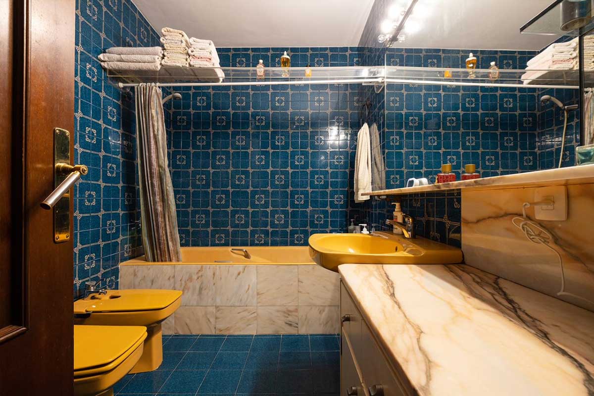 Baño con azulejos azules y sanitarios en amarillo