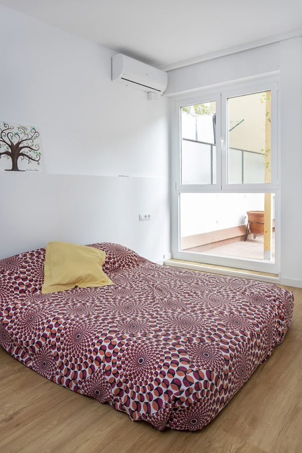 Dormitorio principal con sábanas geométricas y acceso a terraza