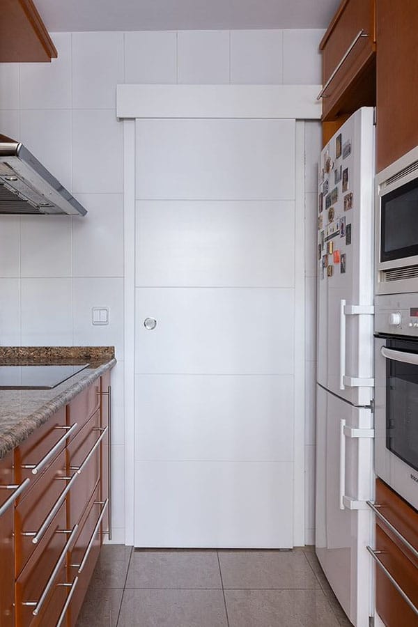 Puerta de una cocina alargada con mobiliario a ambos lados