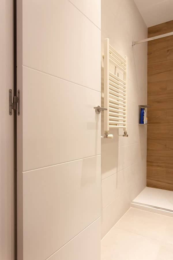 Toallero eléctrico junto a ducha reformada con revestimiento efecto madera