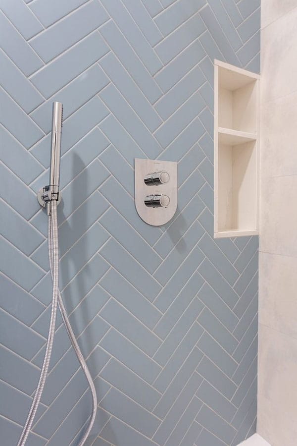 Interior de la ducha con pared azul y espacio de almacenamiento integrado