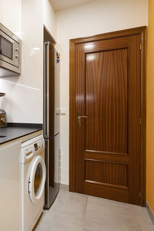 Puerta de cocina en madera oscura junto a lavadora