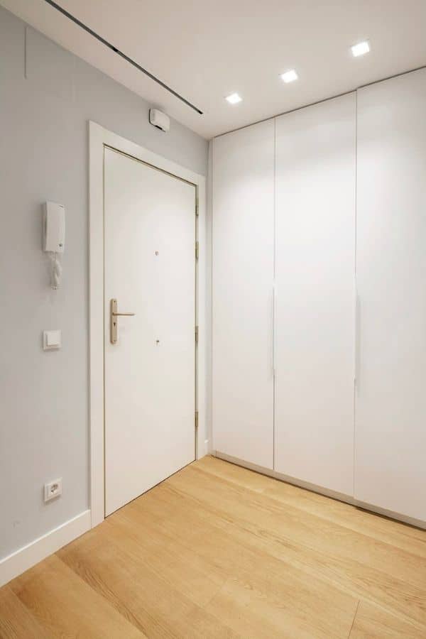 Zona de pasillo con puerta y armarios empotrados en blanco